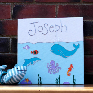 A personalised canvas picture set under the deep blue sea including huge blue whales and sweet dolphins, a long legged octopus, serene seahorse and jazzy fish. Seaweed growing at the bottom of the ocean.