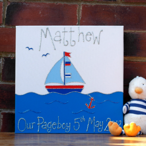 A personalised canvas picture of a small blue sail boat complete with blue flags sailing on the deep blue sea with two birds in the sky and a red anchor in the water. Finished with the child's name and date of birth in silver glitter.