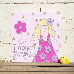 A personalised canvas picture of a little girl wearing and pink and purple flowery dress, with a purple flower in her hair and a pink flower in her hand.