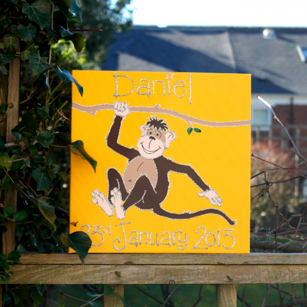 A personalised canvas picture of a chocolate brown monkey holding onto a branch to swing from with a yellow background.