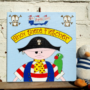 A personalised canvas print of a pirate wearing a red and white stripey shirt and blue waistcoat with an eyepatch and pirates hat. Above the pirate is a banner, skull and cross bones and pirate ship. The pirate has a parrot on its arm.