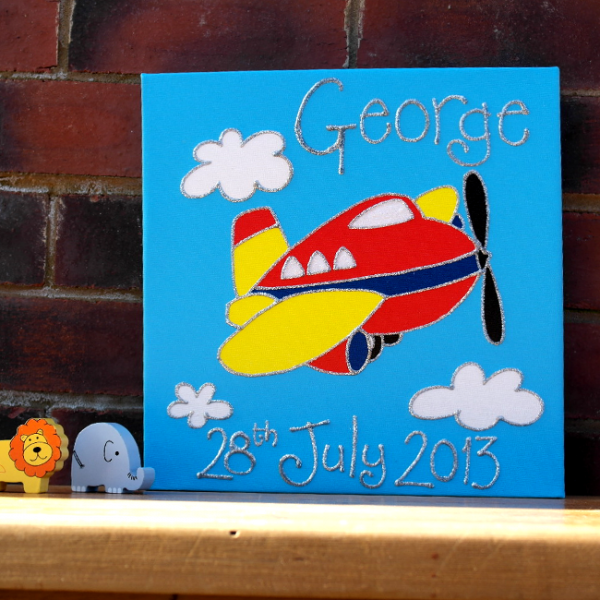 A personalised canvas picture of a red and yellow plane with white windows and a black propeller. White clouds and a blue sky background.