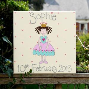 A personalised canvas picture of a princess wearing a pink and blue dress with pink ballerina shoes and a golden crown, surrounding by small baby pink love hearts.