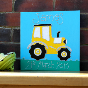 A bold yellow tractor personalised canvas picture with huge black wheels and silver trims. Riding along a deep green field with blue sky background and personalised with childs name and date of birth in glitter.
