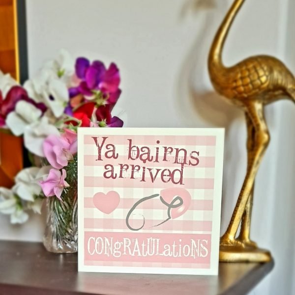 Geordie New Baby Girl card. A pink and white checked card with a pink heart and a pink safety pin. Ya bairns arrived congratulations