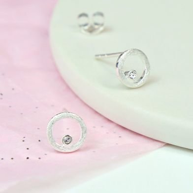 A pair of sterling silver earrings. A small silver circle with a beautiful crystal
