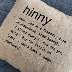 A North East inspired cushion made from hessian and backed with striped ticking. The cushion has a colloquial dictionary quote of what Hinny means.