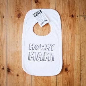 A white bib with poppers around neck to fasten with and on the front is the geordie saying howay mam!