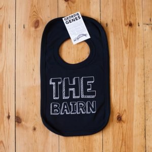 A black bib finished with geordie saying the bairn on the front, complete with poppers to fasten around the neck