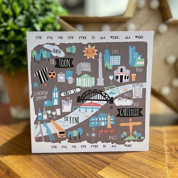 A card with an illustrated map of the tyne with all the Newcastle landmarks and the words to fog on the tyne printed around