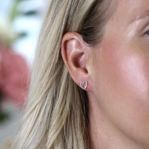 A pair of stud earrings with an open silver hearts with a little gold heart set inside