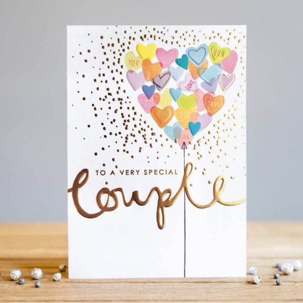 A card covered in hearts with a giant heart shaped balloon made of hearts with the words to a special couple. The word couple is in gold foil