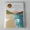 A birthday card with a contemporary depiction of a mountain and beach scene with the words have a beautiful day