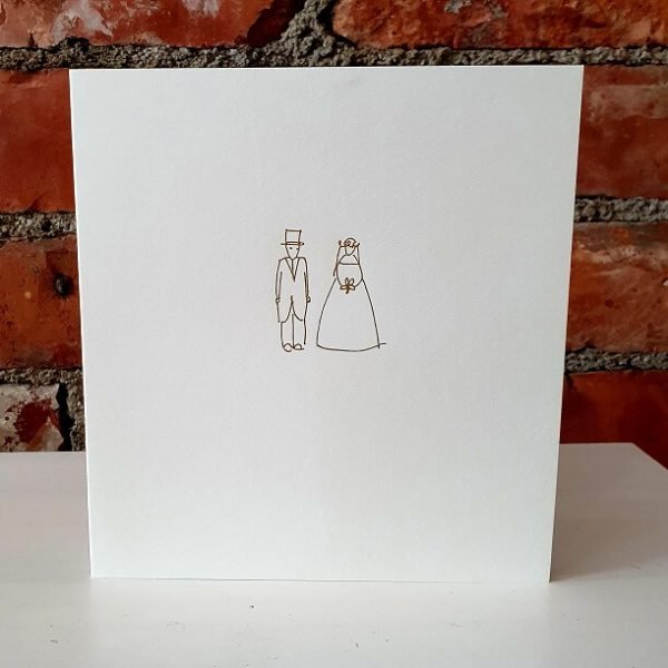 A simple wedding card with a bride and groom printed in gold foil