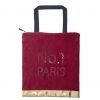 A red velvet bag which has a black handle and a gold strip at the very bottom of the bag. The words No.1 Paris are on the front of the bag made up using sequins.