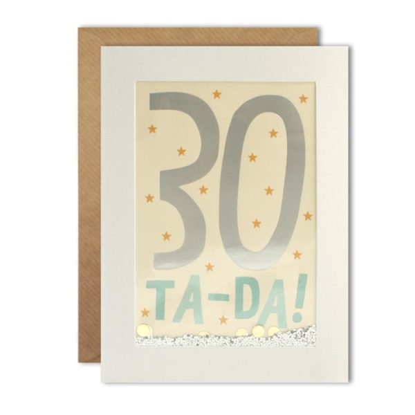 A white rectanuglar card which has a clear cellophane centre with a cream background and the number 30 printed in a foil effect, and the words Ta-Da printed in pale blue. In between the image and the cellophane is glitter and dotty confetti which will move around when it is given a shake. The card comes with a kraft brown envelope.