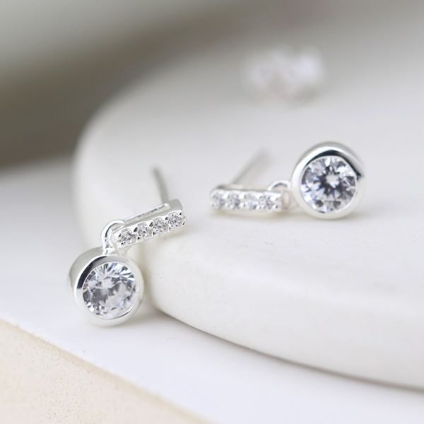 A pair of silver crystal drop earrings. The earrings have a silver bar with 3 cubic zirconia in the bar and a larger cubic zirconia at the end of the bar.