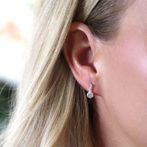 A pair of silver crystal drop earrings. The earrings have a silver bar with 3 cubic zirconia in the bar and a larger cubic zirconia at the end of the bar.