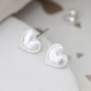 A pair of silver heart studs earrings, which have tiny beading around the edges and the inset section is a brushed or scratched finish.