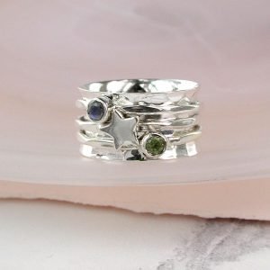 Silver spinning ring with three spinning bands over a wide textured silver ring. The three bands have a silver star, a moonstone and a peridot semi precious stones.