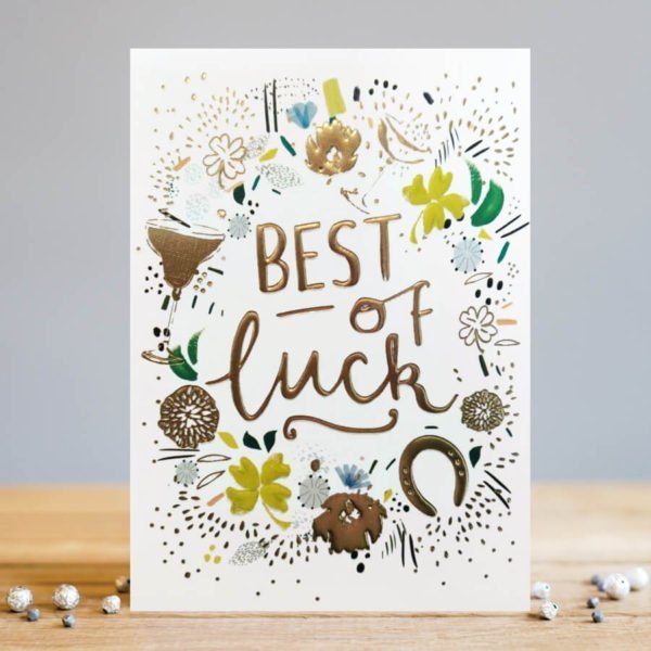 A white rectangular card with the words Best of Luck embossed and printed in a gold foil effect. Around the wording there are painted images of 4 leafed clovers. horse shoes and flowers which als have an embossed gold effect.