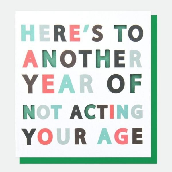 A designer typographic birthday card from Caroline Gardner. A white card with Here's to another year of not acting your age in colourful letters with some of the letters being punched out.