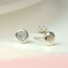 A pair of silver and pearl heart studs. These sterling silver earrings have a pearl heart inset.