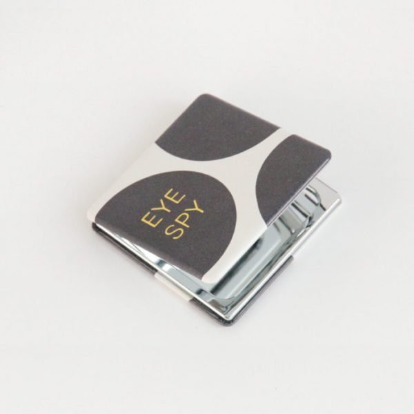 black and white big dot square pocket compact mirror with eye spy written in gold. Leather look with magnetic close and 2 mirrors, one magnifying