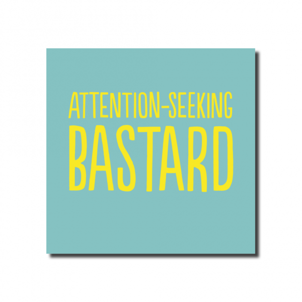 A small square pale blue card with yellow text that says. ATTENTION SEEKING BASTARD