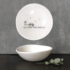 A cream ceramic little dish with a black line drawing of a caravan and the words Good friends, great adventures