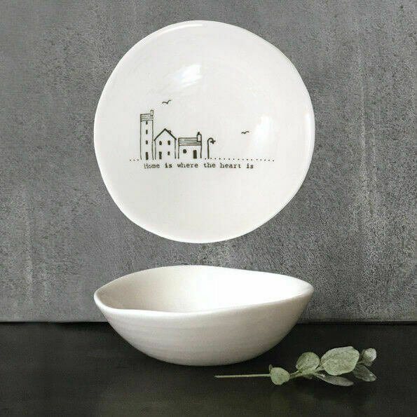 A white porcelain dish with a black line drawing of some cute little houses and the words Home is where the heart is
