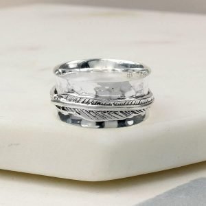Hand made sterling silver ring with a beaten concave band and two slim connected silver feathers, spinning freely around the band.