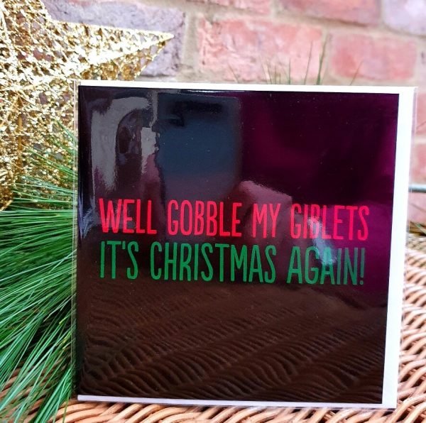 A funny Christmas card. A black card with red and green text that reads Well Gobble My Giblets it's Christmas again.