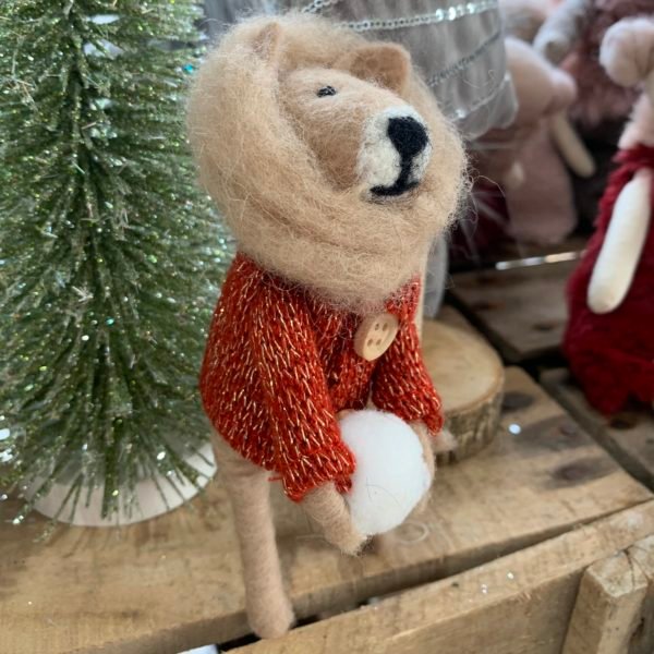 A lion Christmas decoration with a lovely mane, a red jumper and holding a snowball.