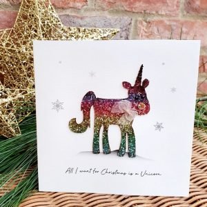 A luxury Christmas card from Five Dollar Shake featuring a Reindeer with a unicorns horn. The reindeer is made of rainbow glitter and has an organza ribbon around his neck. All I want for Christmas is a Unicorn.