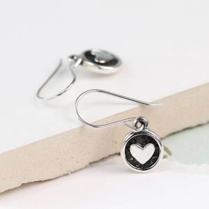 A pair of sterling silver earrings with a silver heart in a disc drop, the disc has been oxidised to black to make the silver heart stand out.