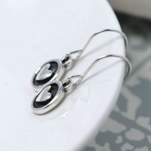 A pair of sterling silver earrings with a silver heart in a disc drop, the disc has been oxidised to black to make the silver heart stand out.