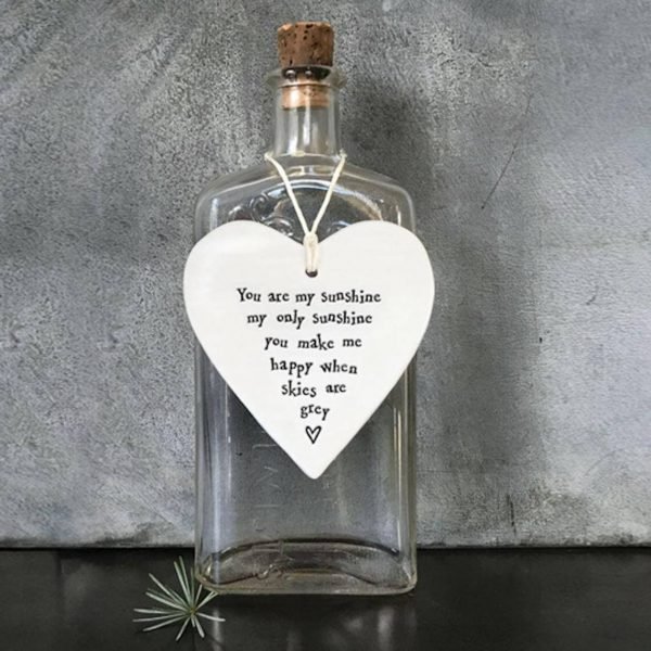 A cream porcelain hanging heart with black stamped writing that reads you are my sunshine my only sunshine you make me happy when skies are grey