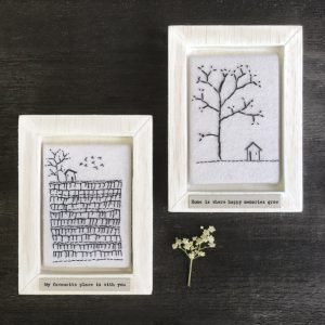 A sweet wooden frame with a square of felt which is embroidered with an image of a field with a tree and a little house. The wording 'My favourite place is with you' printed on it.