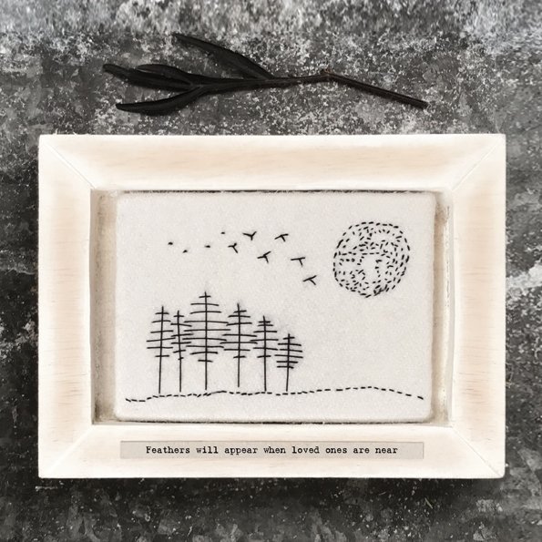 A beautiful framed embroidered piece of felt with an image of trees, birds and the sun. The wording 'Feathers will appear, when loved ones are near' printed on it.