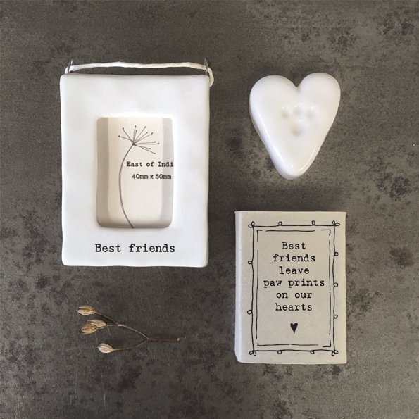A little white ceramic heart with a little paw print in it, kept in a cardboard matchbox with the words 'Best friends leave paw prints on our hearts' printed on it.