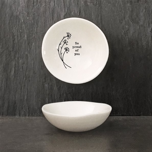 A mini white ceramic trinket dish with a flower design and the words 'So Proud of You' imprinted on it.