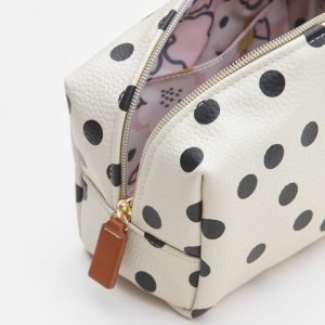 A whitecube cosmetic bag with black spots a brass zip and brown leather tag. Made by British designer Caroline Gardner.