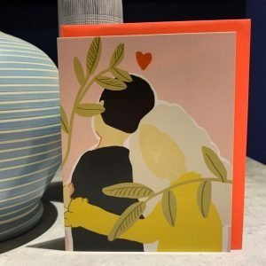 A colourful card with a lovely affectionate couple on it with a love heart printed above them