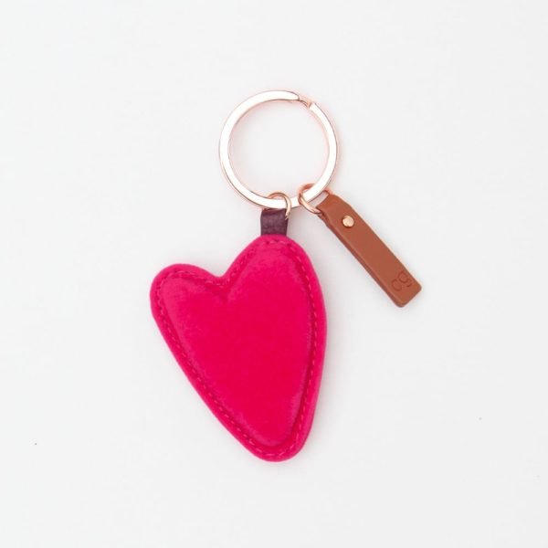 A brightly coloured pink heart shaped keyring with a gold coloured ring and a leather tab, from design company Caroline Gardner.