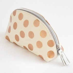 A half moon cosmetic bag with rose gold spot design from British designer Caroline Gardner.