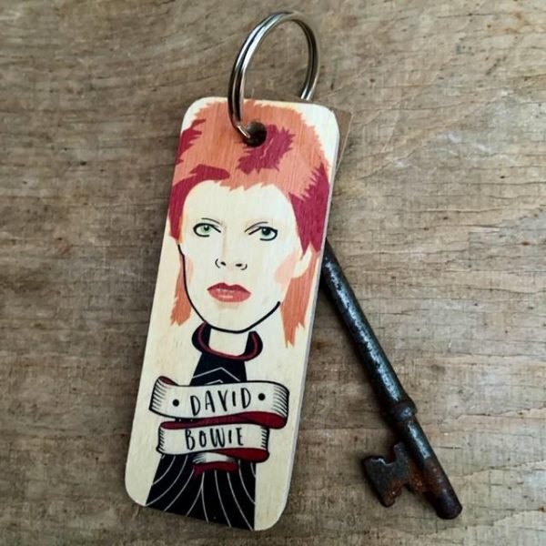 A wooden keyring from Wotmalike with a characterised image of David Bowie on it.