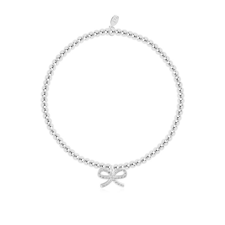 A silver plated elasticated bracelet with an embellished bow charm on it. The bracelet is on a lovely sentiment card with a confetti design all over it. The words A Little Thank You are printed on the card. From Joma Jewellery