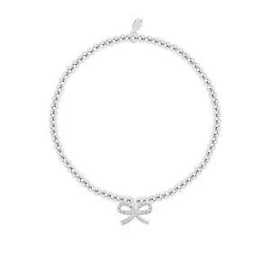 A silver plated elasticated bracelet with an embellished bow charm on it. The bracelet is on a lovely sentiment card with a confetti design all over it. The words A Little Thank You are printed on the card. From Joma Jewellery