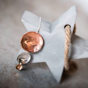 A hand made pendant necklace with 3 hammered discs in decreasing sizes in brass, copper and silver.